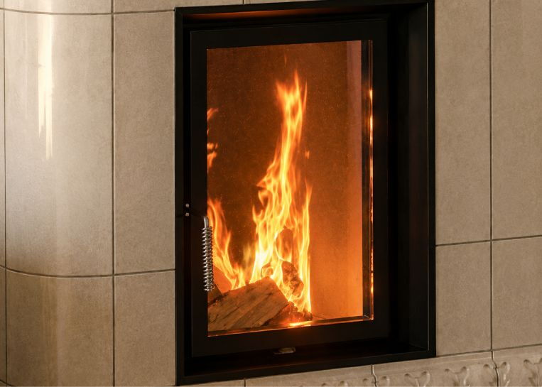 Detaillierte Ansicht des lodernden Feuers im wassergeführten Kesseleinsatz hinter der stabilen Glasscheibe.