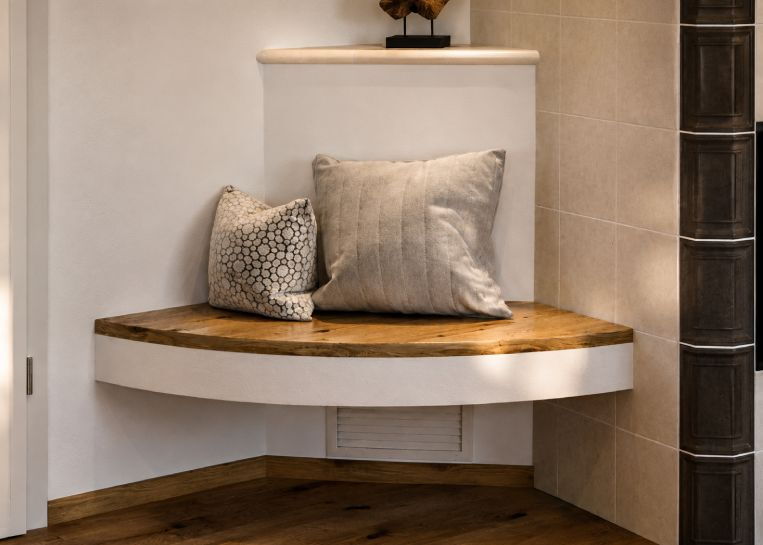 Detaillierte Ansicht der ergonomischen Sitzbank mit massiver Holzauflage auf einem Sockel aus dunkler Feinkeramik.