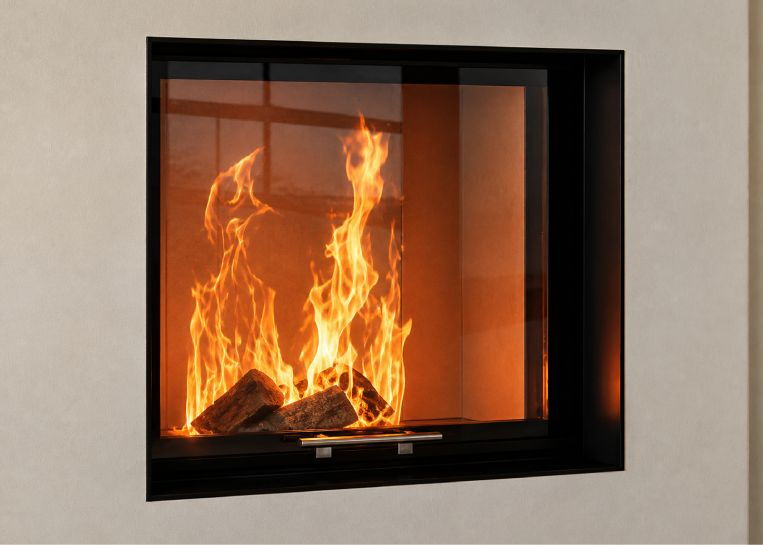 Nahaufnahme des lodernden Feuers hinter der quadratischen Sichtscheibe, perfekt eingerahmt von einer massiven, schwarzen Metallblende.
