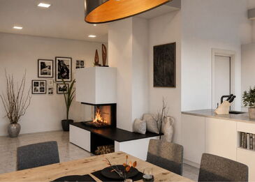 Ein moderner, drei-seitig verglaster Kamin als stilvoller Raumakzent in einem hellen Wohnzimmer mit angrenzendem Essbereich.
