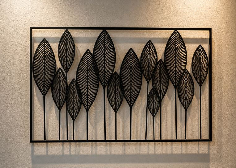 Detailansicht einer kunstvollen Metall-Wanddekoration in Blattform, die das moderne Ambiente der Kaminlandschaft unterstreicht.