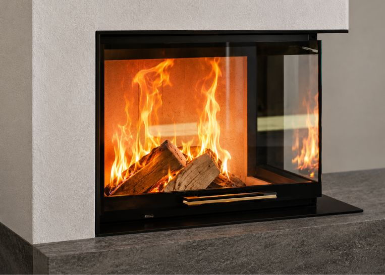 Nahaufnahme des lodernden Holzfeuers hinter dem markanten Ecksichtglas des Neocube C12 Modul-Ofens.
