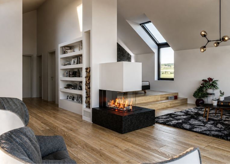Perspektive auf den Gaskamin, der als zentrales Design-Element das offene Loft-Wohnzimmer mit angrenzendem Schlafbereich verbindet.