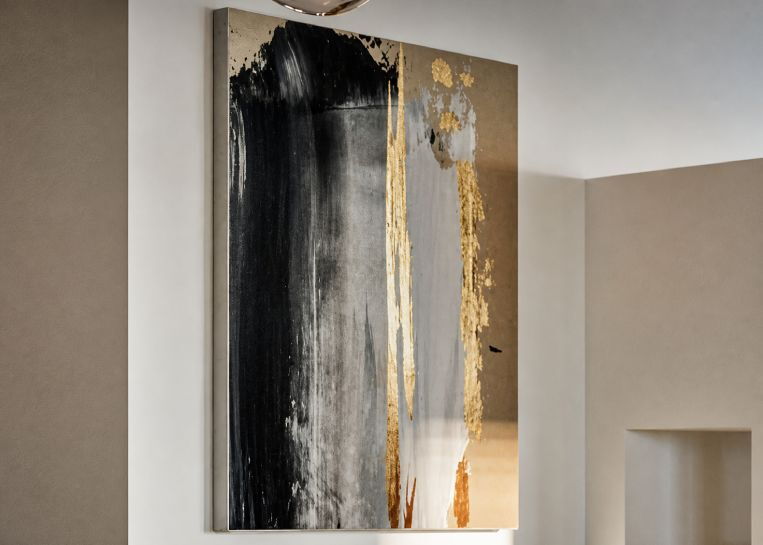 Detailansicht eines abstrakten Gemäldes in Gold- und Schwarztönen, das perfekt mit dem Design des modernen Kamins harmoniert.