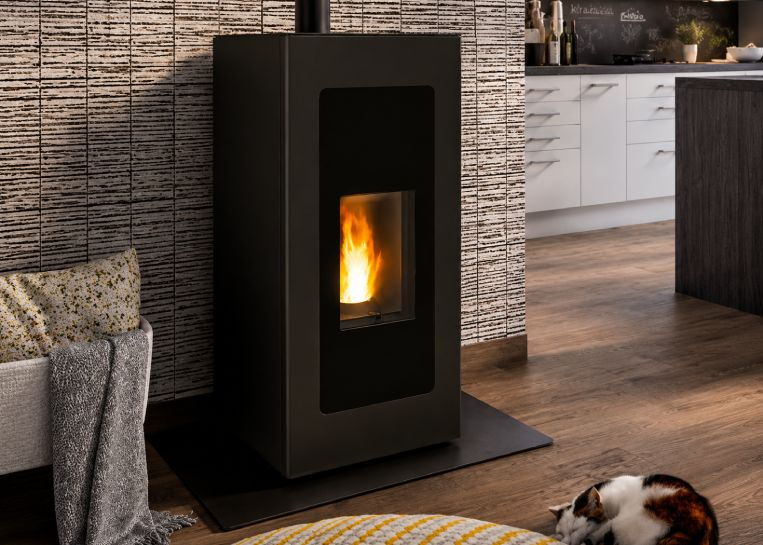 Frontalansicht des schwarzen Pelletofens mit Fokus auf die ruhige Flamme und das moderne, rechteckige Gehäuse.