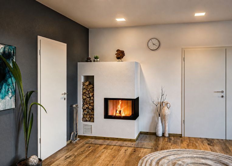 Perspektive auf den Eckkamin im Raumgefüge; das minimalistische Design harmoniert mit dem warmen Holzfußboden und der dunklen Akzentwand.