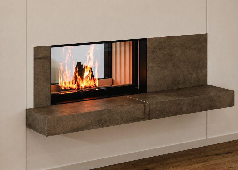 Detaillierte Ansicht des freischwebenden Feuertischblocks aus keramischen Platten und der massiven schwarzen Metallblende am Kamineinsatz.