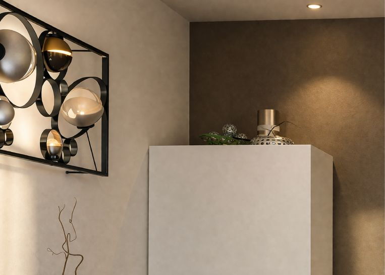 Detaillierte Ansicht der eleganten, weißen Kalkspachtelung des deckenhohen Kaminverbaus neben modernen Design-Leuchten.