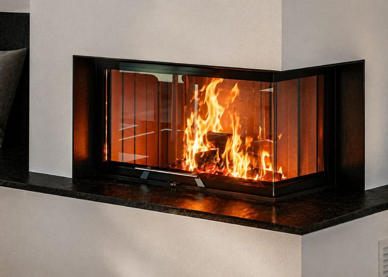 Detaillierte Ansicht des lodernden Feuers durch die Ecksichtscheibe des Spartherm Varia AS-2R, eingerahmt von einer massiven schwarzen Blende.