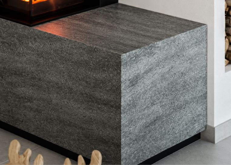 Nahaufnahme der Ofenbank aus Sinterkeramik im Farbton Basalt Grey, die einen eleganten Kontrast zum weißen Korpus bildet.