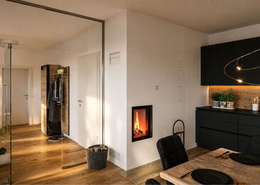 Ansicht des minimalistisch weiß verputzten Kombiofens mit Brunner HKD 2.2f Einsatz und Glasschutzplatte auf Parkettboden.