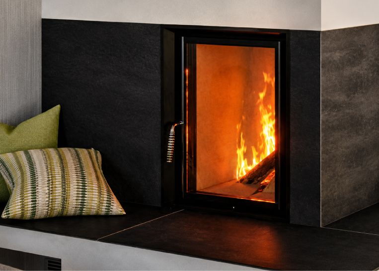 Nahaufnahme der großen Sichtscheibe (46x57 cm) mit loderndem Holzfeuer im Brunner Tunnelkombiofen.