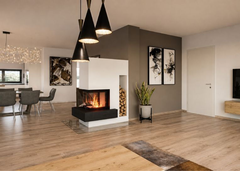 Perspektive auf den Kamin-Raumteiler mit Fokus auf das bündig integrierte Holzlager und die harmonische Wohnraumgestaltung.