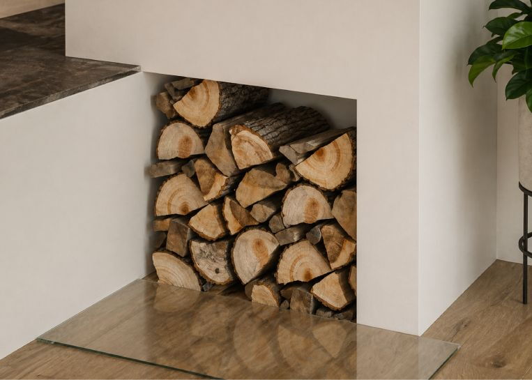 Detailansicht der praktischen, bündig in den Ofenkörper integrierten Holznische, die das geradlinige Design auflockert.