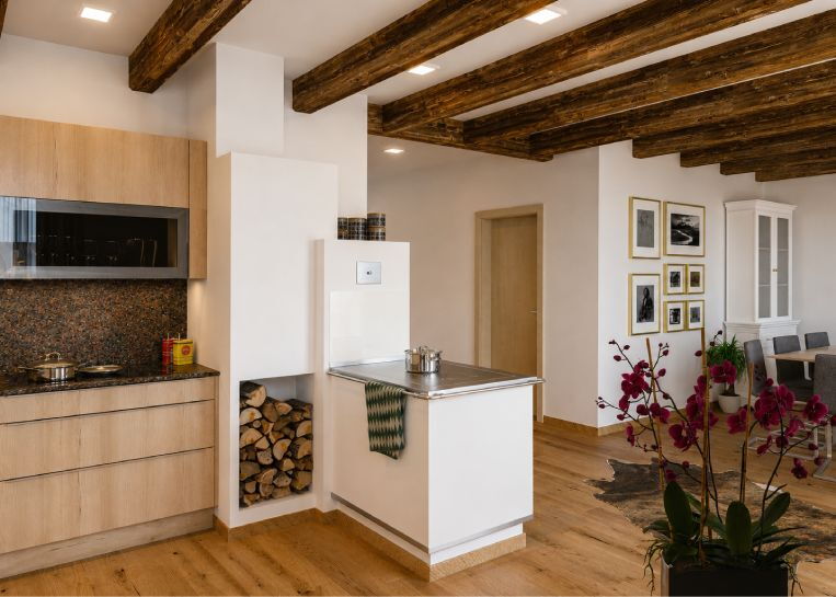 Ein schlichter, weiß verputzter Aufsatzherd mit Panorama-Sichtscheibe und aufgesetztem Backrohr in einem modernen Holzhaus.