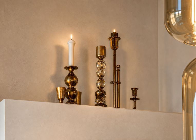 Nahaufnahme von stilvollen, goldenen Kerzenständern auf der weißen Kaminabdeckung, die das puristische Design der Anlage unterstreichen.