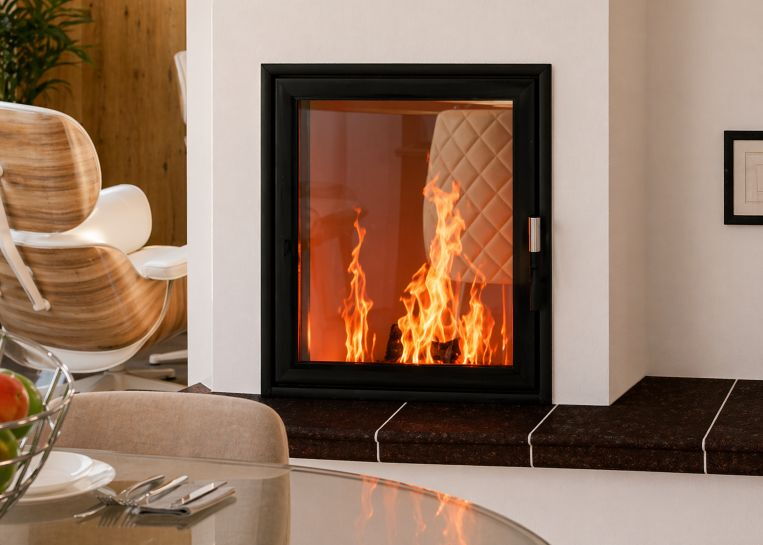 Nahaufnahme des brennenden Holzfeuers im Spartherm Linear Mini Z1 51 Kamineinsatz, eingerahmt von einer schwarzen Metallblende.