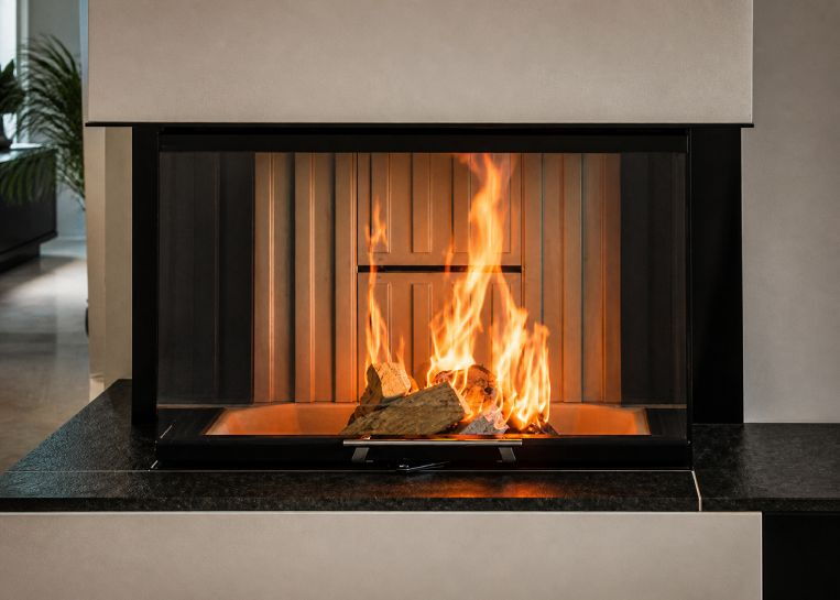 Nahaufnahme des lodernden Feuers hinter der drei-seitigen Panoramascheibe, eingerahmt von einer schwarzen Metallblende.