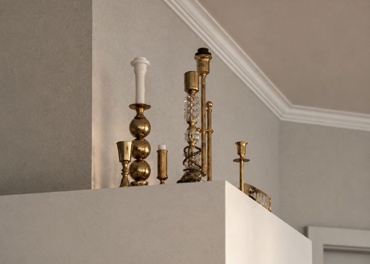Elegante Messing-Kerzenständer auf der keramischen Abdeckung des Ofenkörpers als stilvolles Detail.